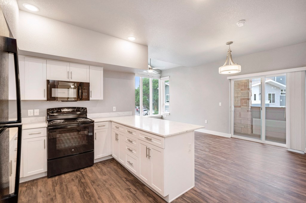 an empty kitchen with white cabinets and a black stove and refrigerator