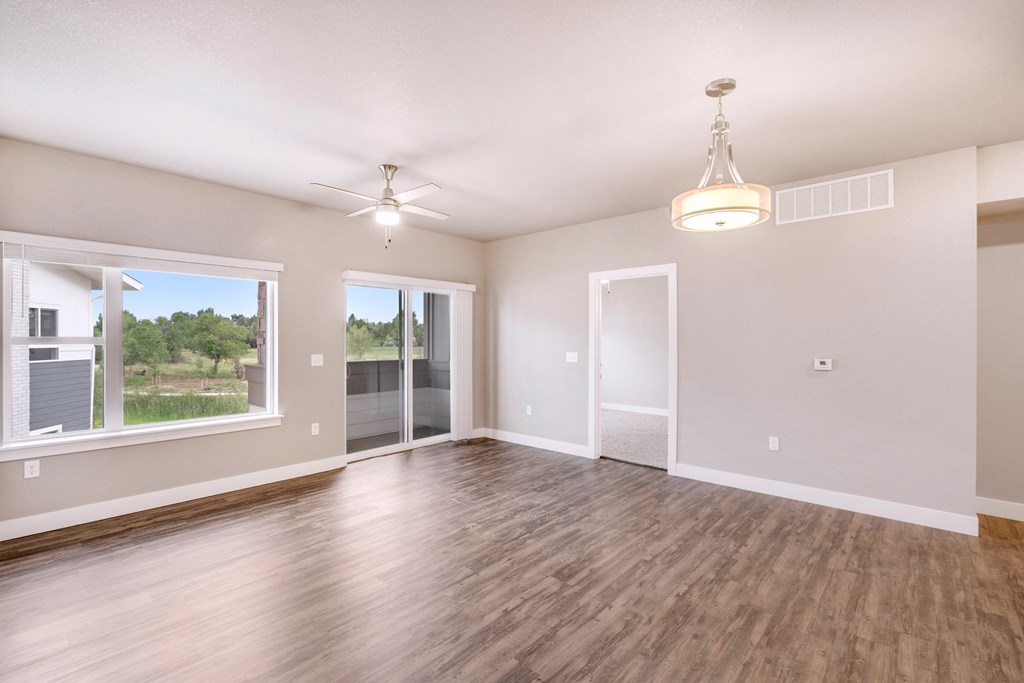 an empty living room with a window and a ceiling fan