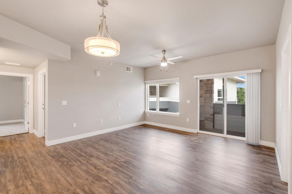 an empty living room with a ceiling fan and a window