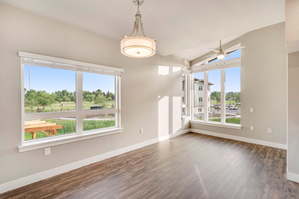 an empty living room with large windows and a ceiling fan