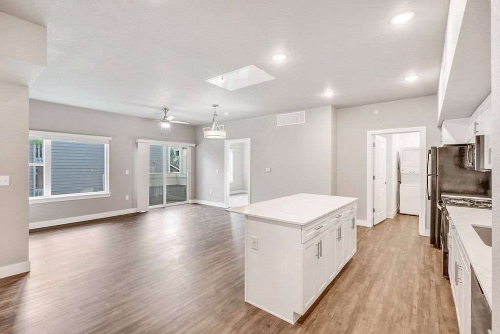 an open kitchen and living room with white cabinets and a white counter top