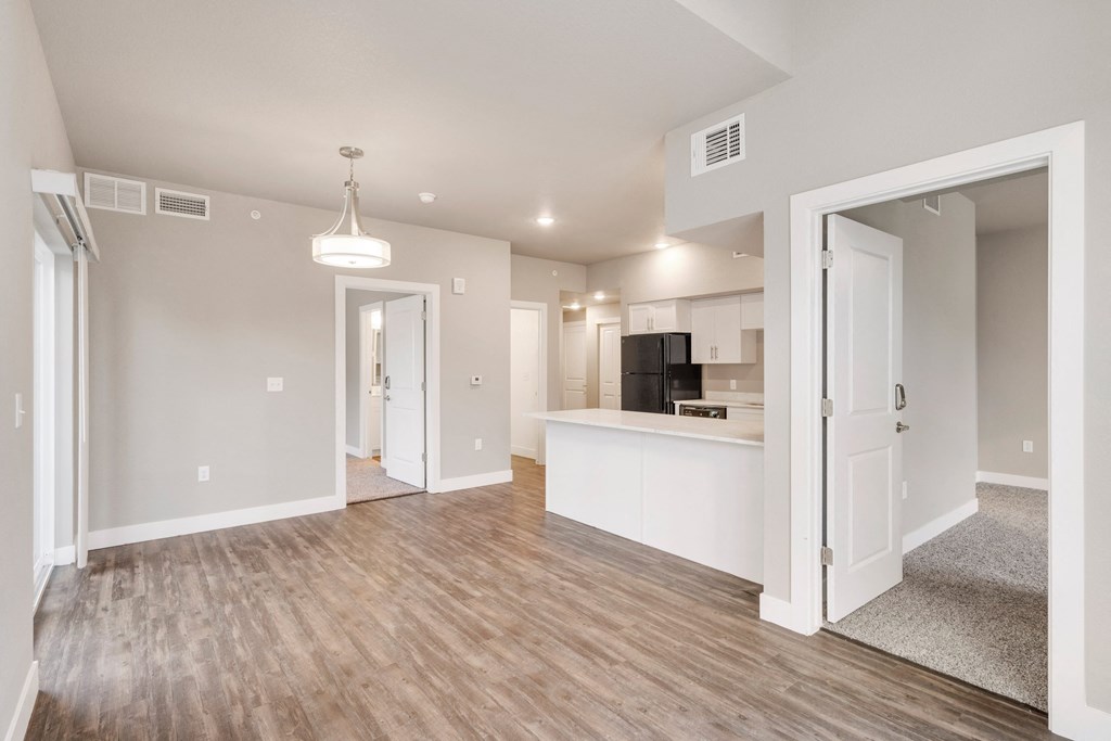 a renovated living room and kitchen with white walls and wood flooring
