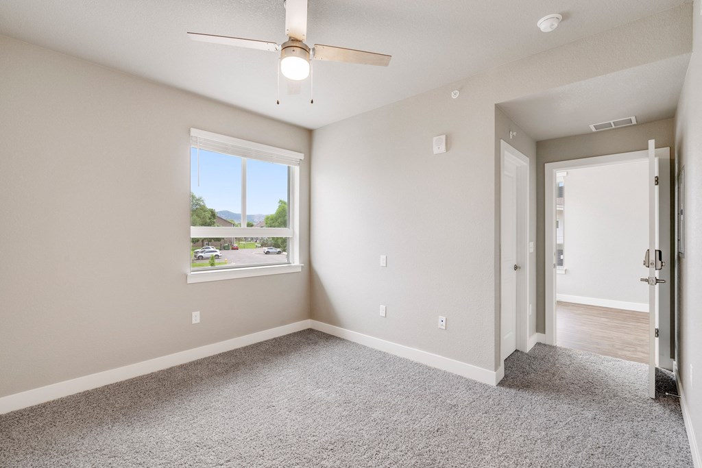an empty bedroom with a ceiling fan and a window