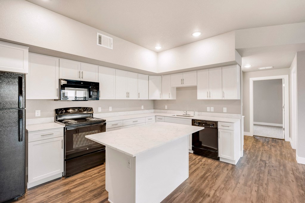 a large white kitchen with white cabinets and black appliances