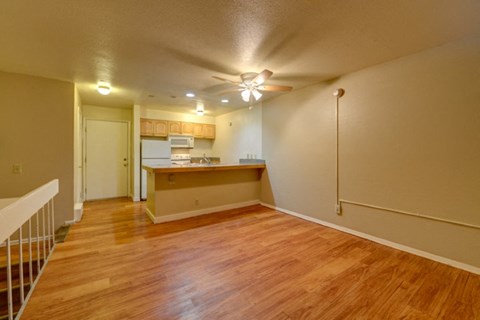 an empty living room and kitchen with a wood floor