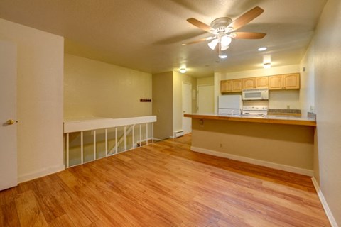 an empty living room and kitchen with a wood floor
