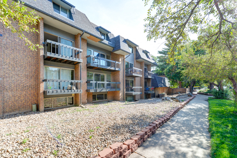 an empty sidewalk in front of an apartment building