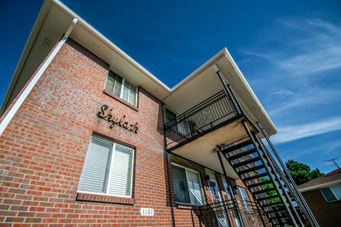 a brick apartment building with a staircase and a blue sky in the background