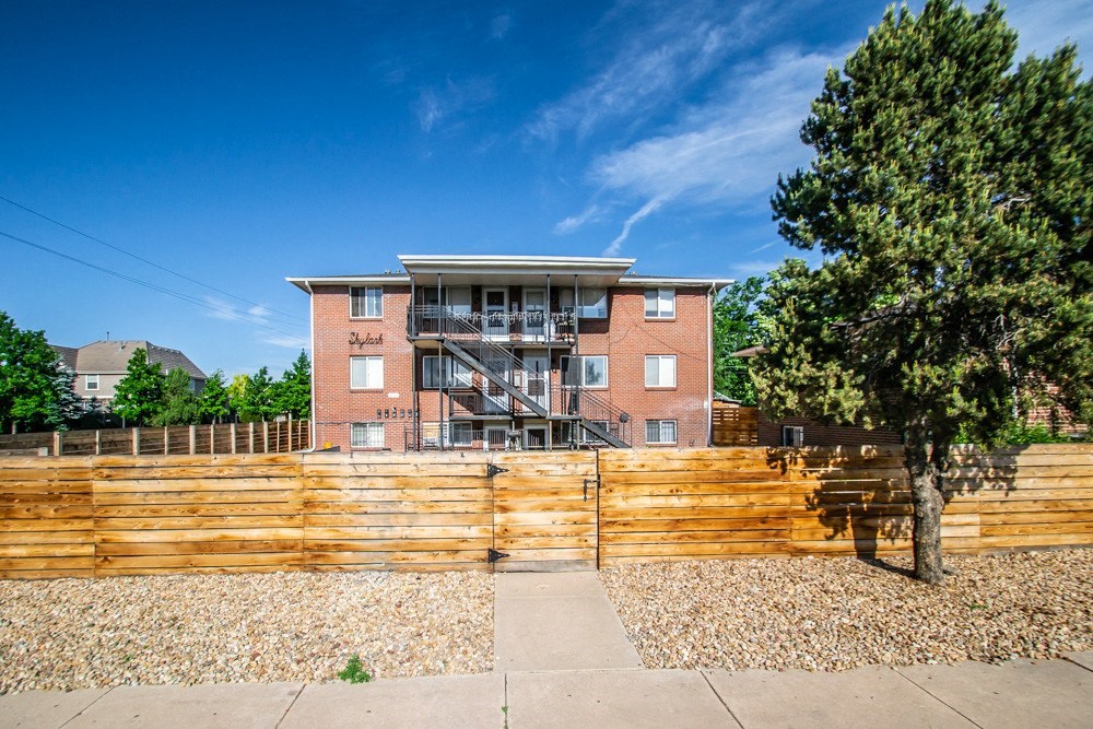 a brick apartment building with a wooden fence in front of it