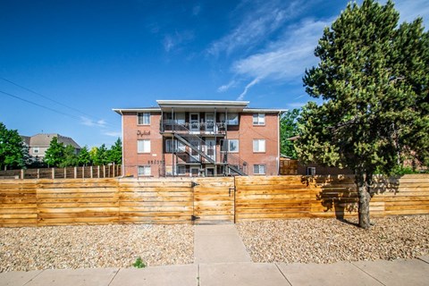 a brick apartment building with a wooden fence in front of it