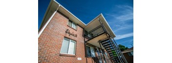 a brick apartment building with a staircase and a blue sky in the background