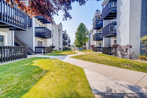 A row of apartment buildings with a sidewalk and green grass.