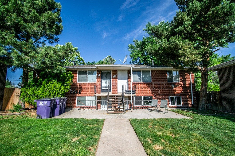 a house with a yard and a purple trash can in front of it