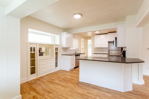 A kitchen with white cabinets and a wooden floor.