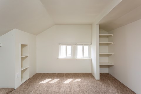 A room with a window and a carpeted floor.