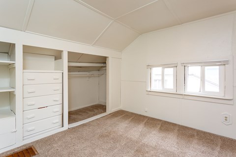 A room with a carpeted floor and a window with white blinds.