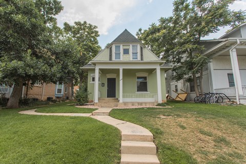A house with a green front yard and a white fence.