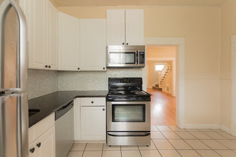 A kitchen with white cabinets and a black stove top oven.