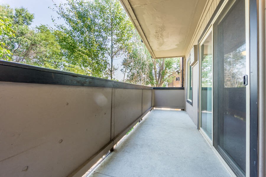 a long balcony with glass doors and trees in the background