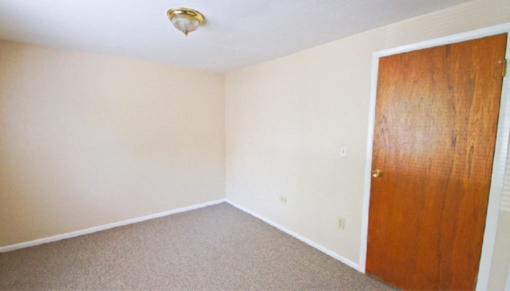 an empty room with a wooden door and a carpet
