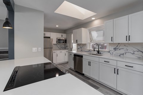 a kitchen with white cabinets and a white counter top and a black stove