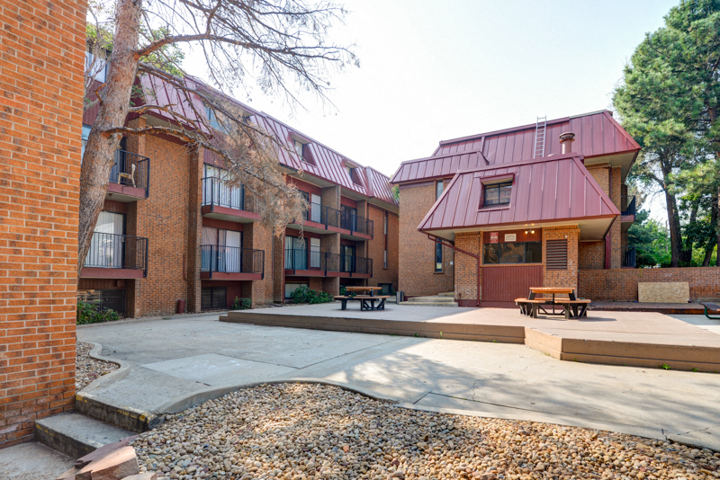 A red brick building with a red roof and a courtyard in front.