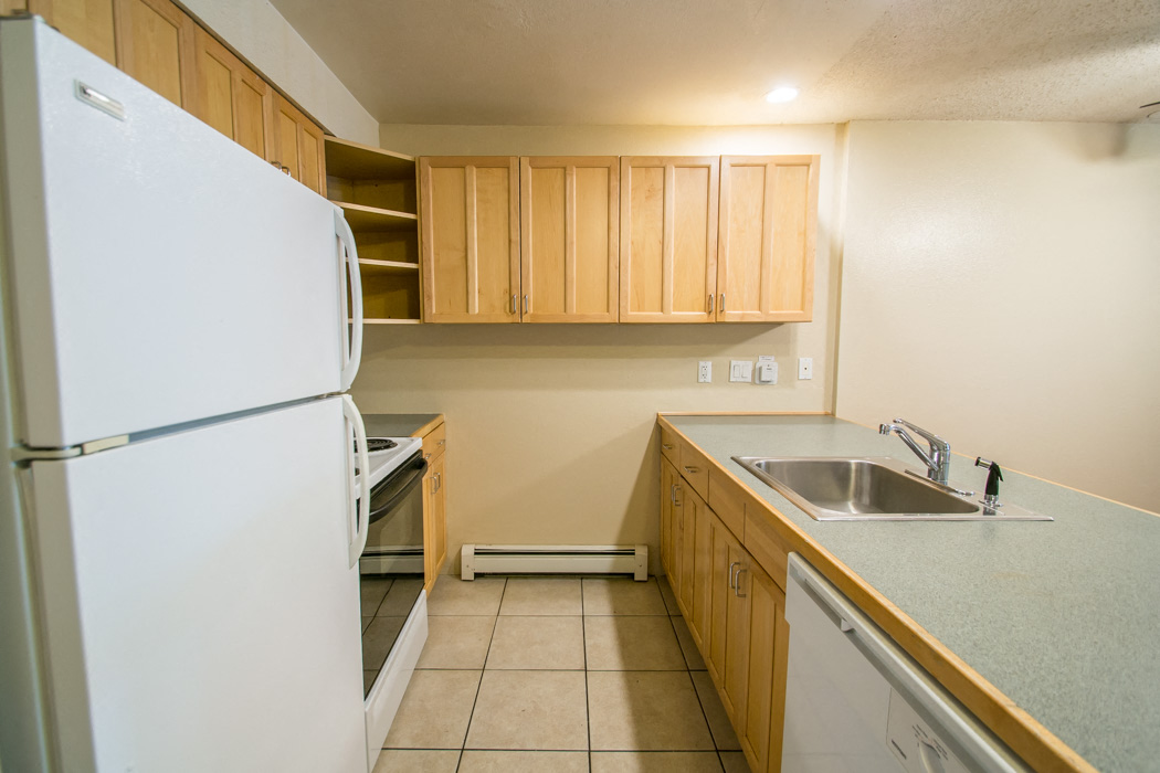 A kitchen with a white refrigerator and wooden cabinets.