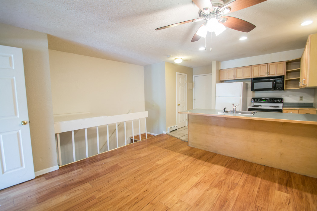 A room with a ceiling fan and wooden floors.