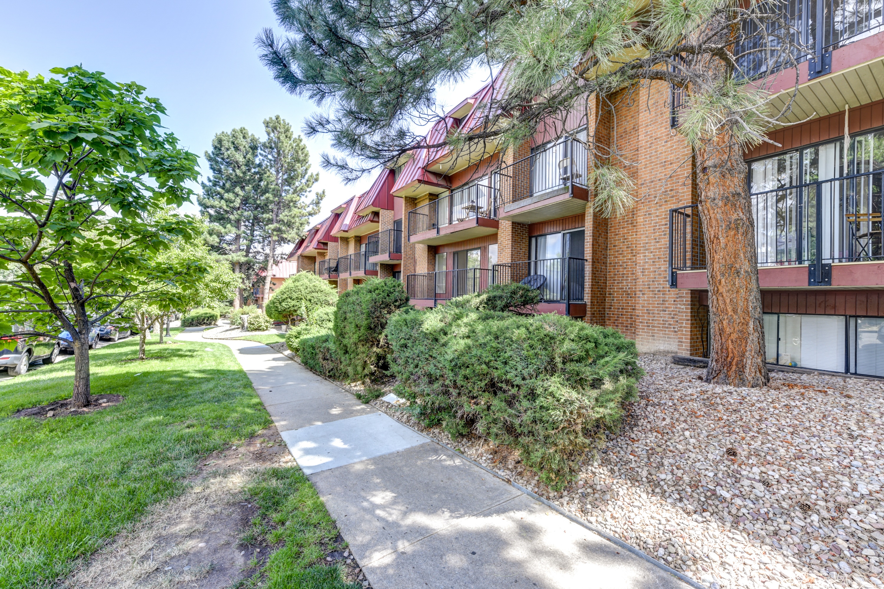 a sidewalk in front of a brick apartment building with trees