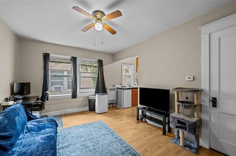 A living room with a blue couch and a ceiling fan.
