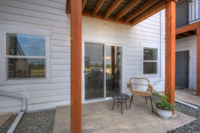 a patio with a chair and a potted plant in front of a sliding glass door