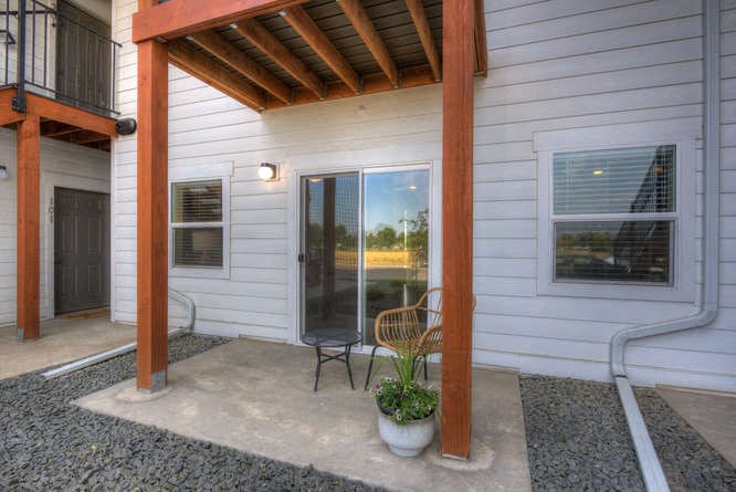 a patio with a chair and a potted plant in front of a door