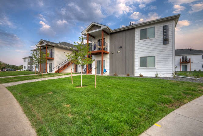 a group of buildings with white siding and a green lawn