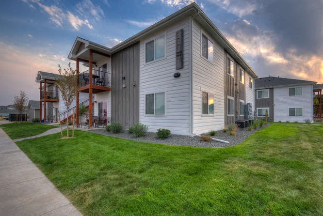 exterior view of the building at dusk with green grass and a walkway in front of it