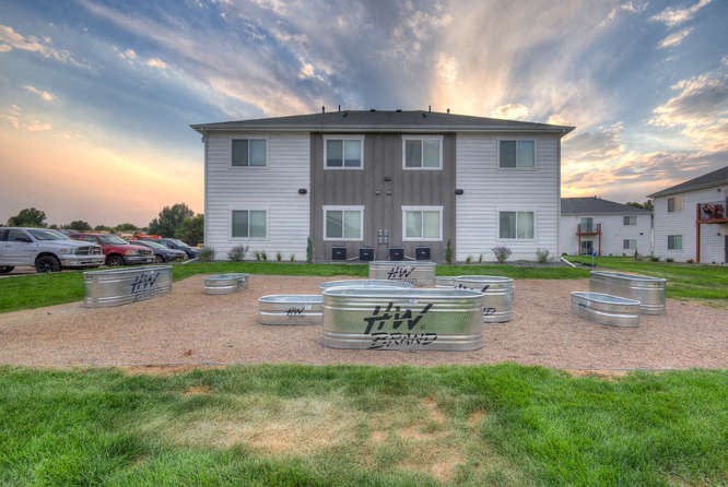 a group of stainless steel tanks sit in a gravel area in front of a white building