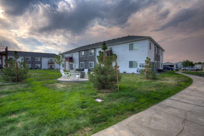 an apartment building with a patio and trees in front of it