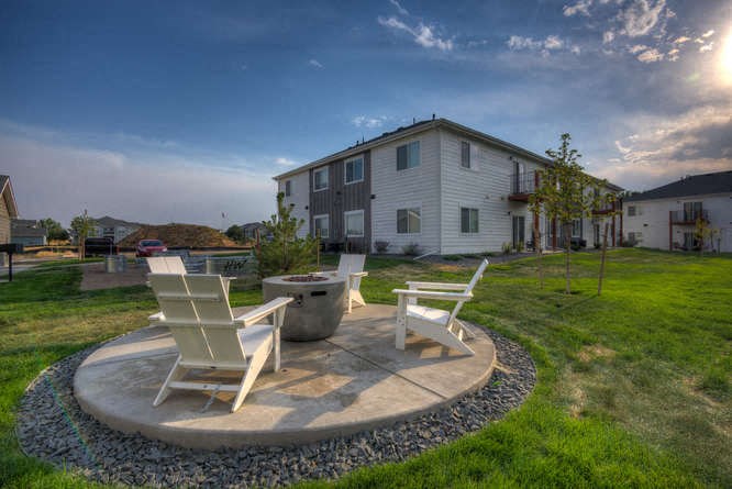 two chairs and a fire pit in the backyard of an apartment complex