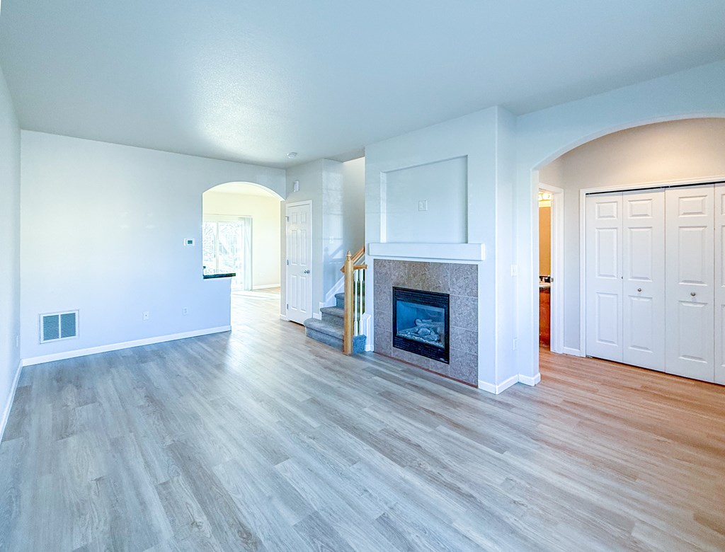 A spacious living room with a fireplace and wood flooring.