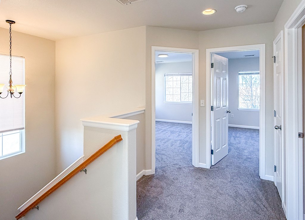 A room with a carpeted floor and a chandelier hanging from the ceiling.