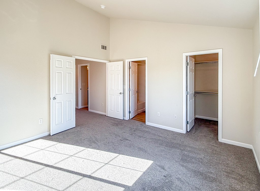 A room with a carpeted floor and three open doors.