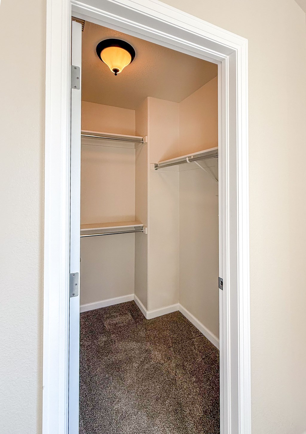A white door is open to a small, empty room with a carpeted floor.