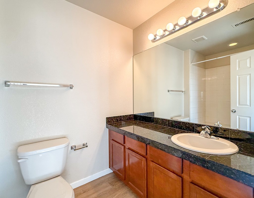 A bathroom with a toilet, sink, and mirror.