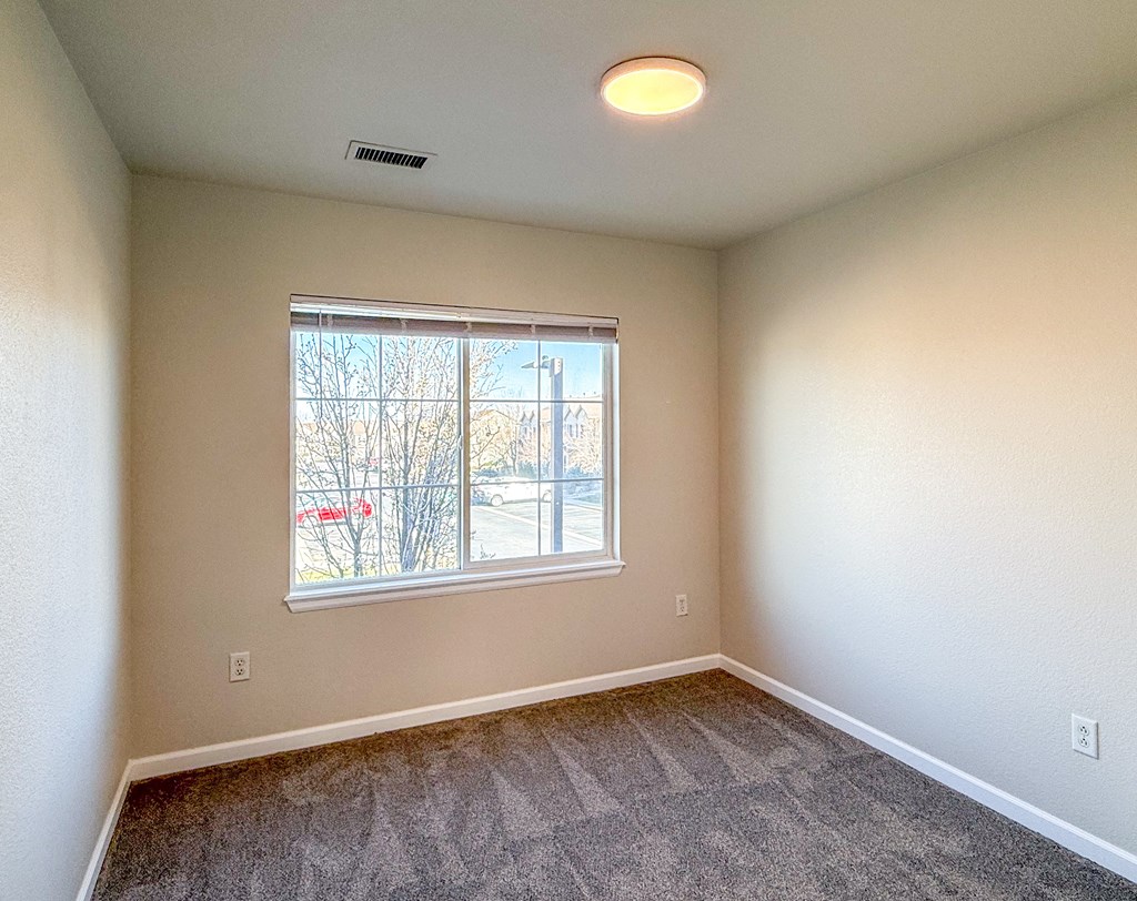 A room with a window and a car parked outside.