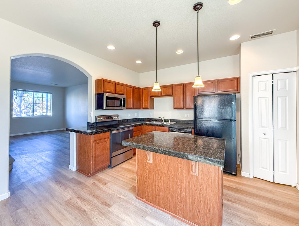 A kitchen with wooden cabinets and a black refrigerator.