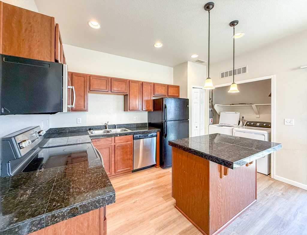 A kitchen with wooden cabinets and a black countertop.