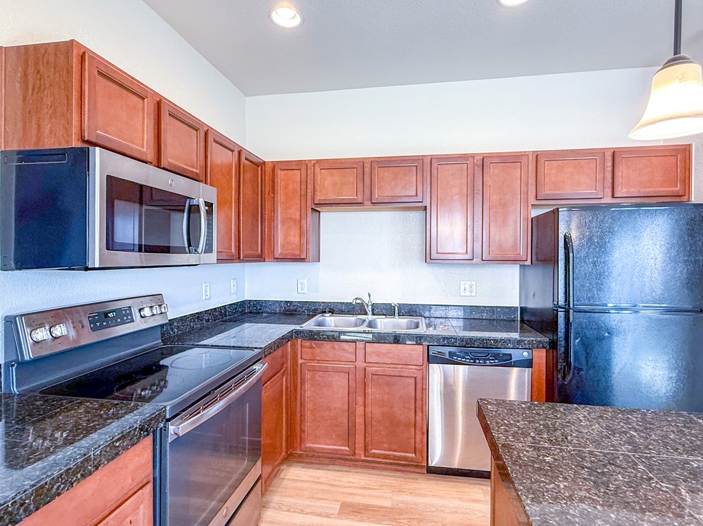 A kitchen with black appliances and brown cabinets.