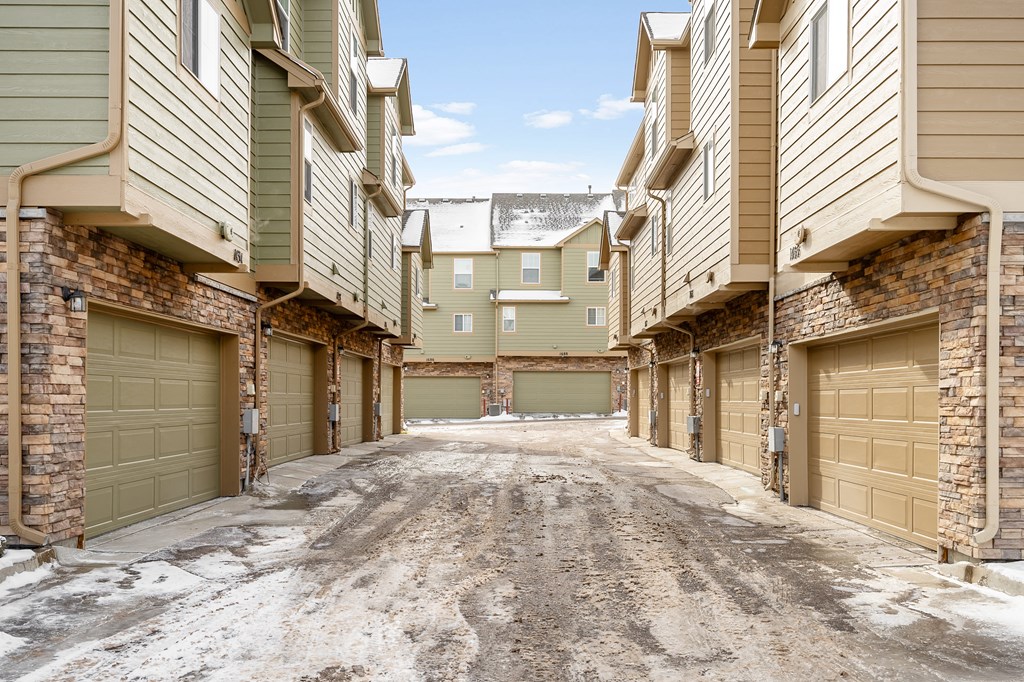 A snowy alleyway between apartment buildings.