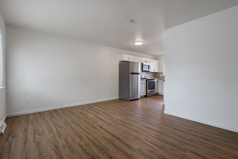 A kitchen with a refrigerator, microwave, and oven in a room with wooden floors.