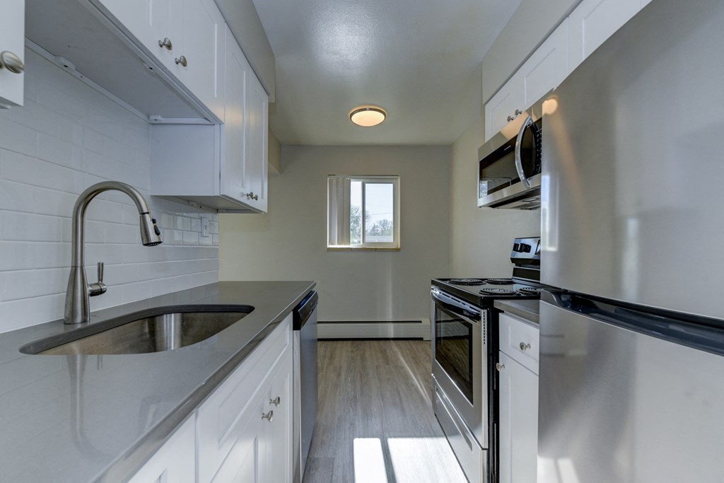 an empty kitchen with white cabinets and stainless steel appliances