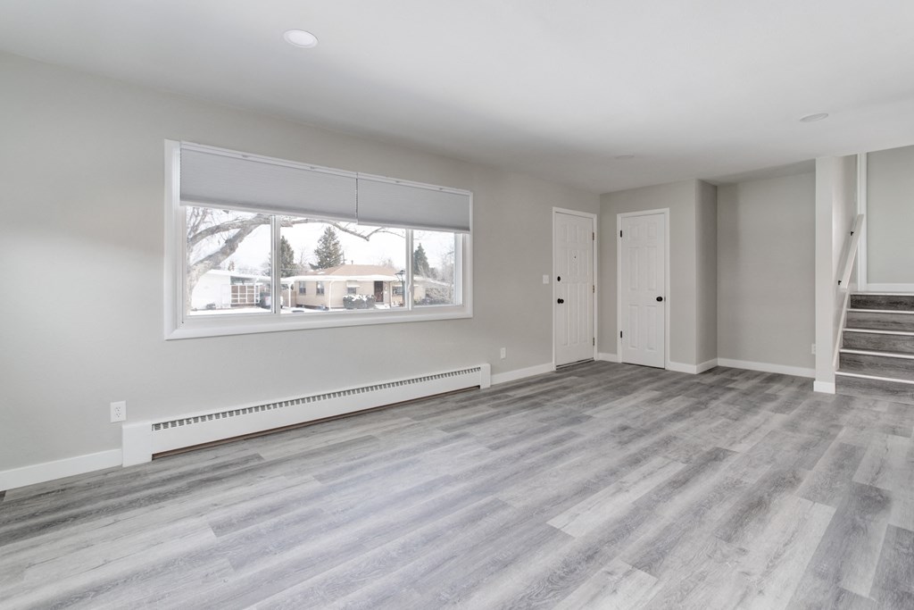 an empty living room with wood floors and a large window